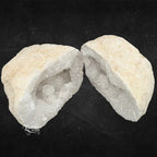 Deux moitiés d'une géode de quartz blanc montrant la croûte rocheuse beige et le cœur cristallin.