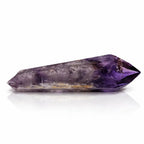 Une vue rapprochée d'une pointe d'améthyste cathédrale polie, mettant en valeur son dégradé de violet intense et sa forme cristalline effilée, sur un fond blanc avec reflet.