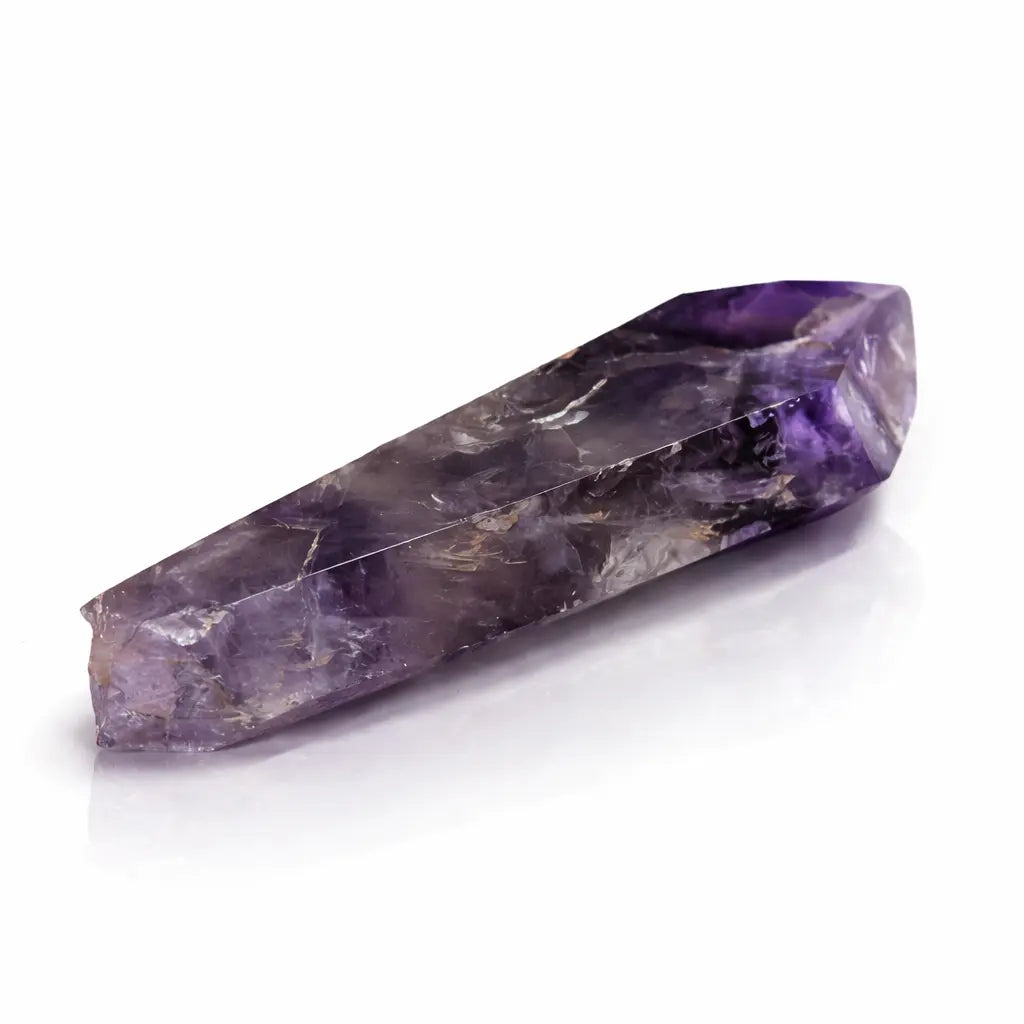 Une pointe d'améthyste cathédrale polie, présentant des nuances de violet profond et des inclusions naturelles, disposée à l'horizontale sur un fond blanc avec reflet.