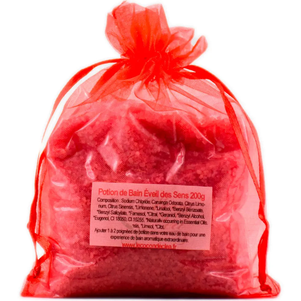 Sachet en organza rouge vif rempli de sels de la Potion de bain Éveil des Sens sur fond blanc.