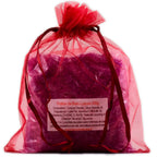 Sachet en organza rouge vif rempli de sels violets de la Potion de bain Luxure sur fond blanc