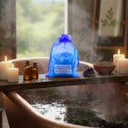 Sachet bleu de Potion de Bain Relaxante sur une planche en bois, eau bleue et cristaux de sel dans une baignoire cuivrée.