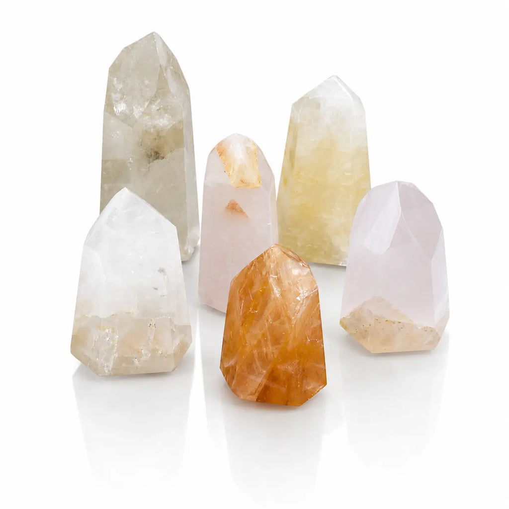 Groupe de six pointes en cristal de roche et quartz hématoïde aux nuances transparentes, blanches et orangées sur fond blanc.