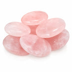 Petit empilement de plusieurs galets de quartz rose polis, lisses et translucides, présentés sur fond blanc.
