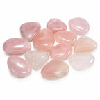Collection de plusieurs galets polis en quartz rose aux formes arrondies et teintes douces, étalés sur fond blanc.