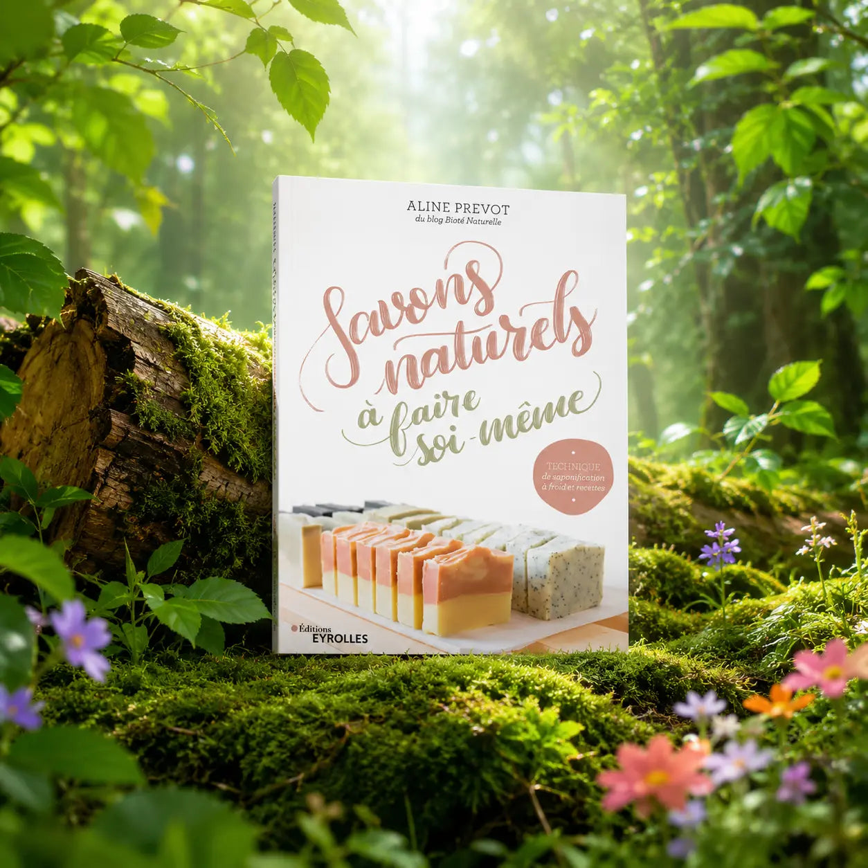 Livre Savons Naturels à Faire Soi Même - Aline Prévôt sur mousse sacrée au pied d'un arbre, entouré de fleurs violettes sous des rayons de soleil magiques.