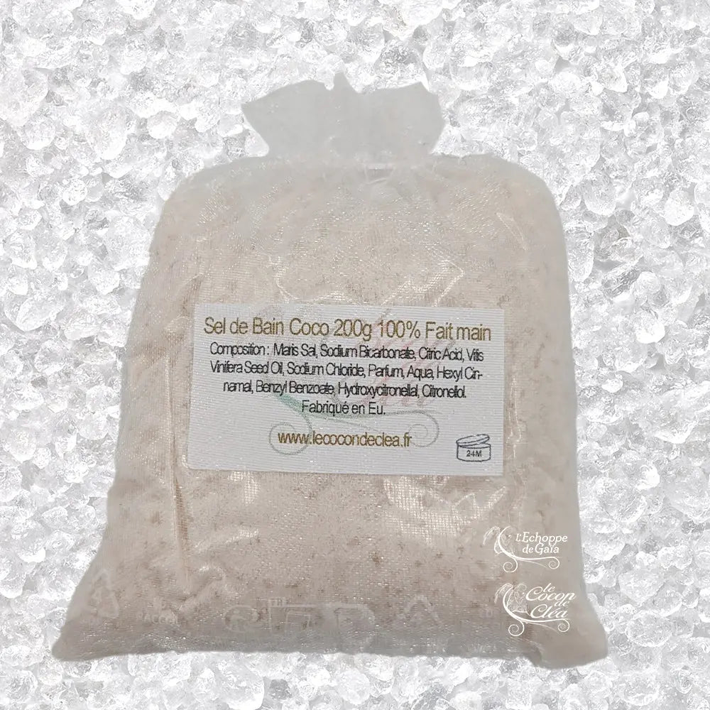 Sachet en organza blanc rempli de Sel de bain coco artisanal 200g sur un fond de cristaux blancs.