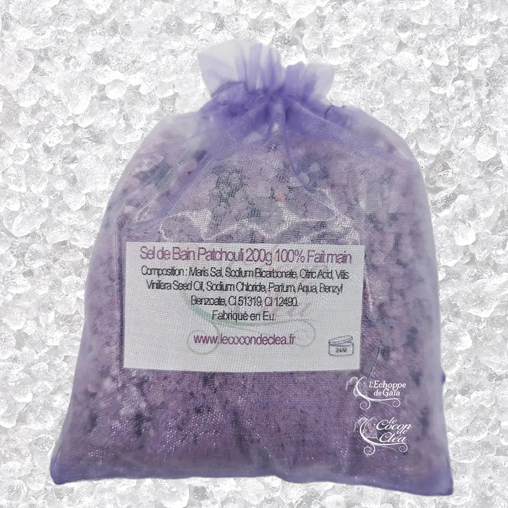 Sachet en organza violet rempli de Sel de bain patchouli artisanal 200g sur un fond de cristaux blancs.