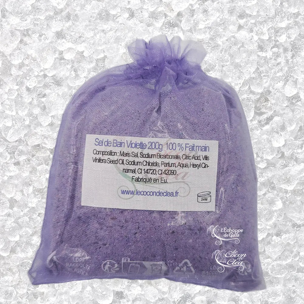 Sachet en organza mauve rempli de Sel de bain violette artisanal 200g sur un fond de cristaux blancs.