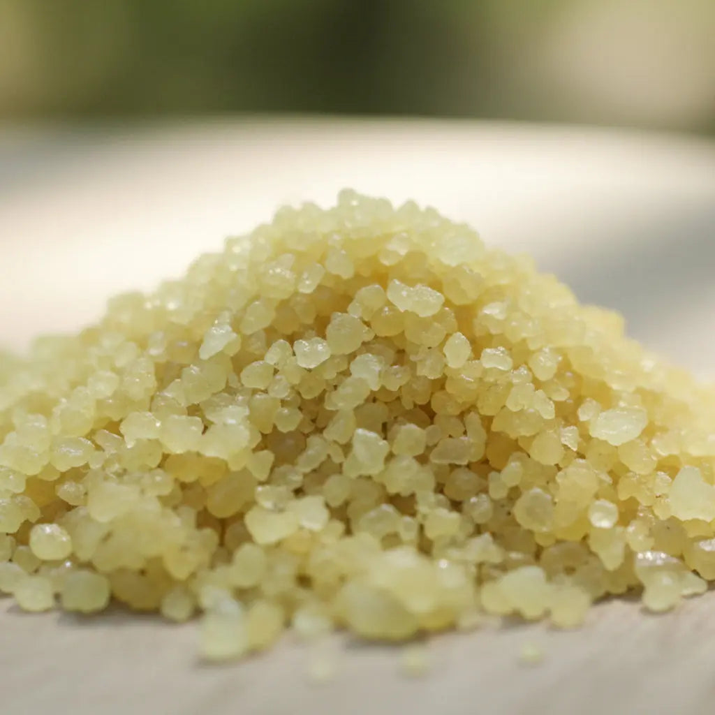 Petit tas de cristaux irréguliers et translucides jaune pâle de sel infusé relaxation.