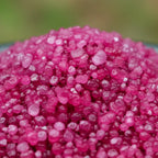 Gros plan sur des cristaux de sel infusé Zone de Confort, texture cristalline rose fuchsia.