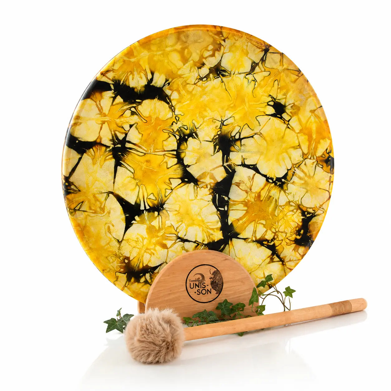 Tambour chamanique circulaire aux motifs craquelés jaune et noir, posé sur un socle Unis-Son décoré de lierre avec sa mailloche, sur fond blanc.