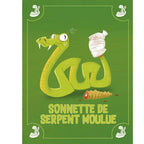 Carte illustrée du jeu Top Witch représentant un serpent vert blessé avec la queue bandée à côté de sa sonnette coupée, sur fond vert avec l'inscription Sonnette de serpent moulue.