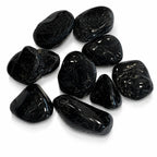 Lot de pierres roulées en tourmaline noire aux surfaces lisses et brillantes sur fond blanc.